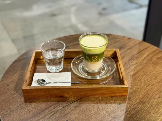 Matcha latte kèm ly nước lọc trên bàn gỗ